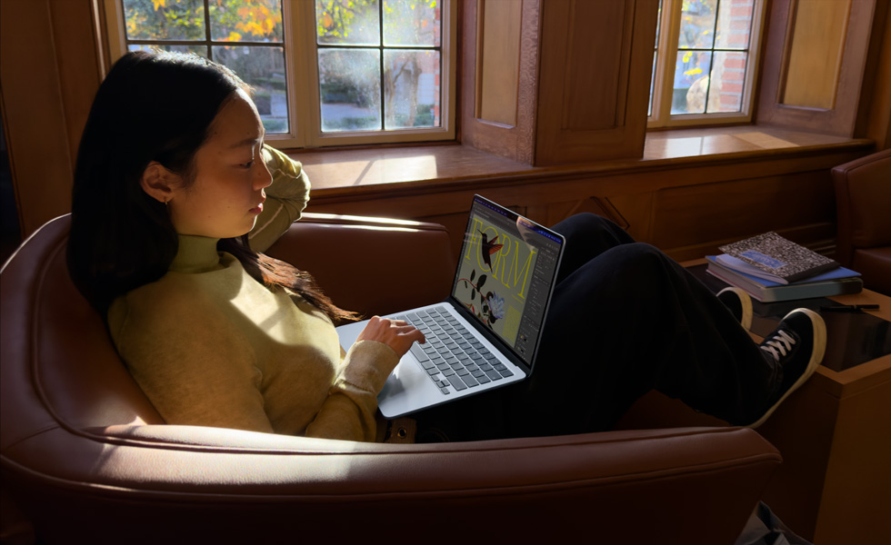 Egy fotelben ülő ember MacBook Airt használ