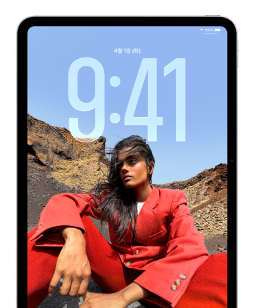 앉아 있는 사람 뒤로 시간이 크게 표시된 iPad 잠금 화면