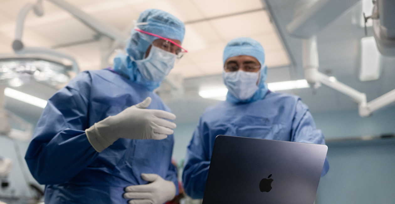 جراحان يناقشان أمراً على شاشة MacBook&nbsp;Pro في غرفة العمليات.